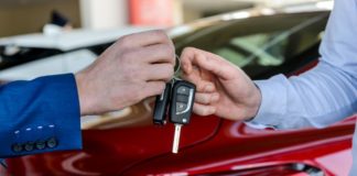 Dealer giving keys to customer in showroom - Buying a car online