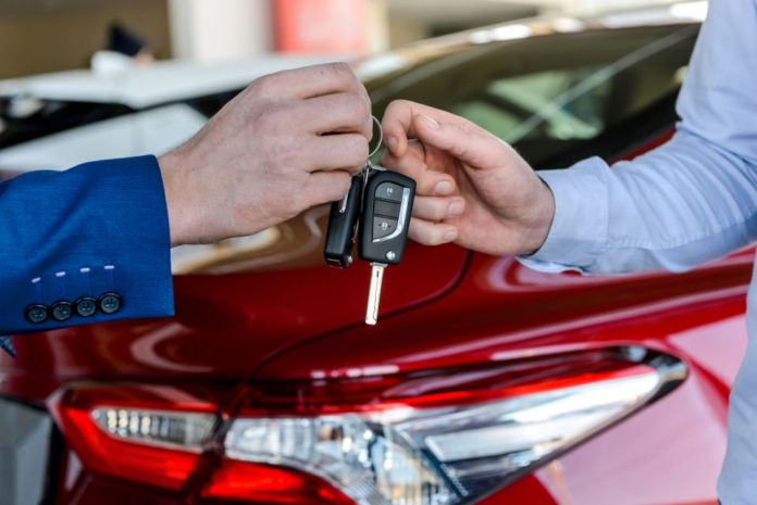 Dealer giving keys to customer in showroom - Buying a car online