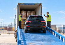 Car being loaded into a shipping container alongside palletised household goods