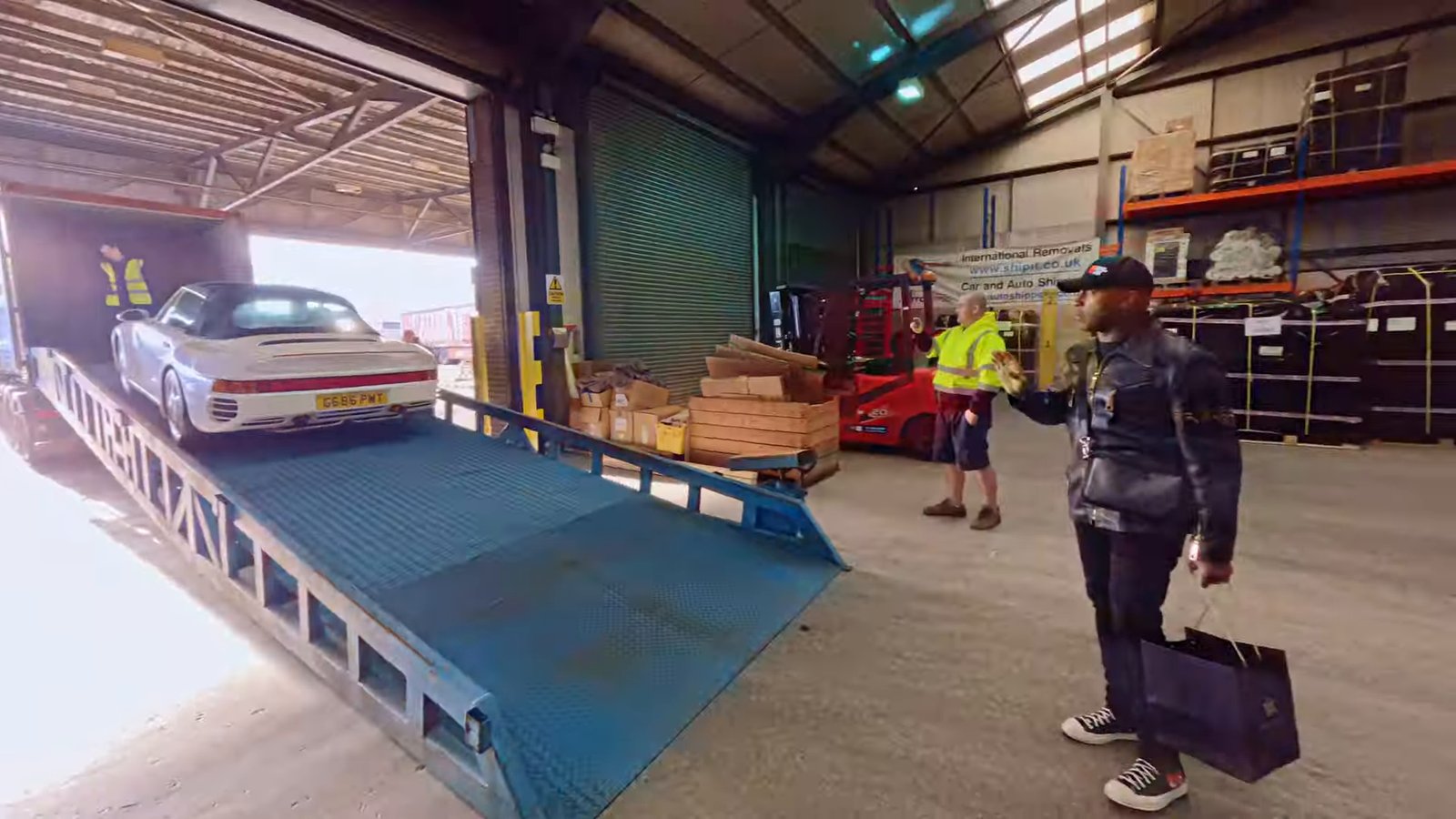 Nigel Benn waves farewell as his Porsche 959 replica is loaded at the AutoShippers UK loading facility